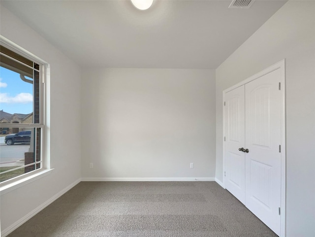 unfurnished bedroom with multiple windows, carpet flooring, and a closet