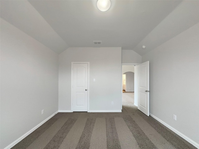 unfurnished bedroom with lofted ceiling and dark carpet