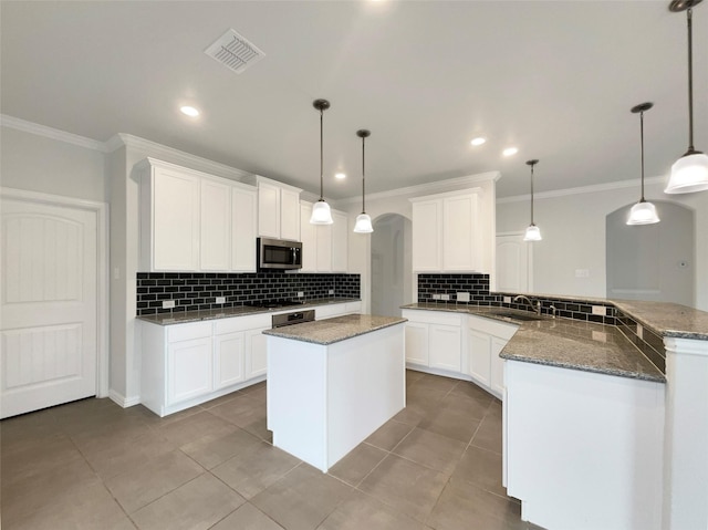 kitchen with hanging light fixtures, ornamental molding, white cabinets, and kitchen peninsula