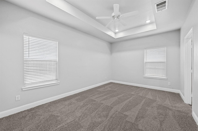 carpeted empty room with ceiling fan and a raised ceiling