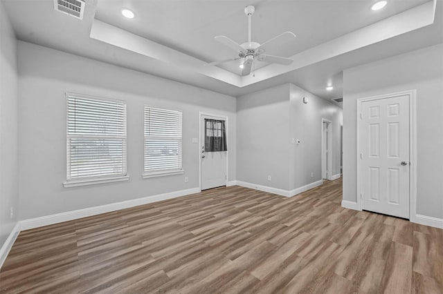 interior space featuring a raised ceiling, ceiling fan, and light hardwood / wood-style floors