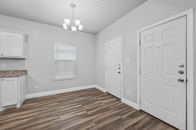 unfurnished dining area with dark hardwood / wood-style floors and an inviting chandelier