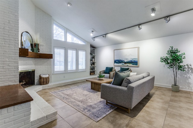 tiled living room with rail lighting, high vaulted ceiling, a wealth of natural light, and a fireplace