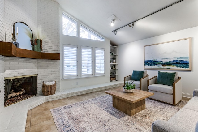 tiled living room with rail lighting, lofted ceiling, and a brick fireplace