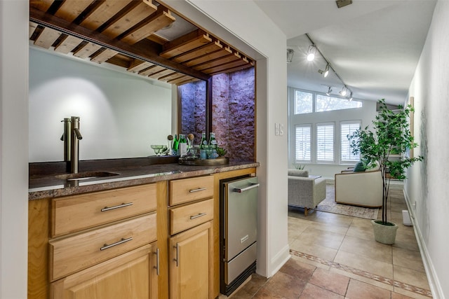 bar featuring vaulted ceiling, sink, light tile patterned floors, track lighting, and light brown cabinets