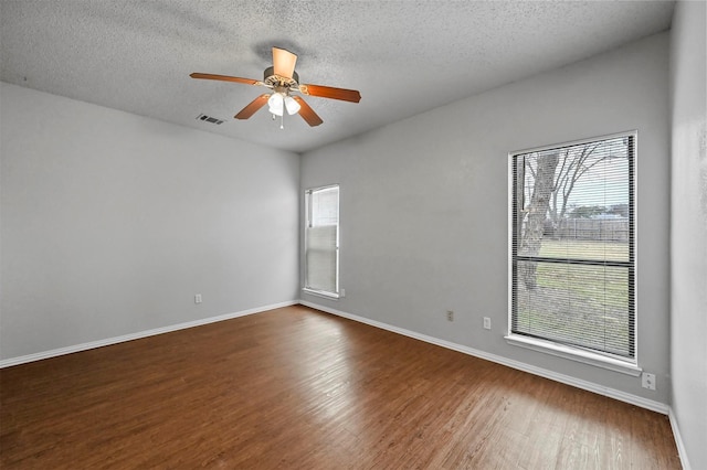 unfurnished room with a wealth of natural light, dark hardwood / wood-style floors, and a textured ceiling