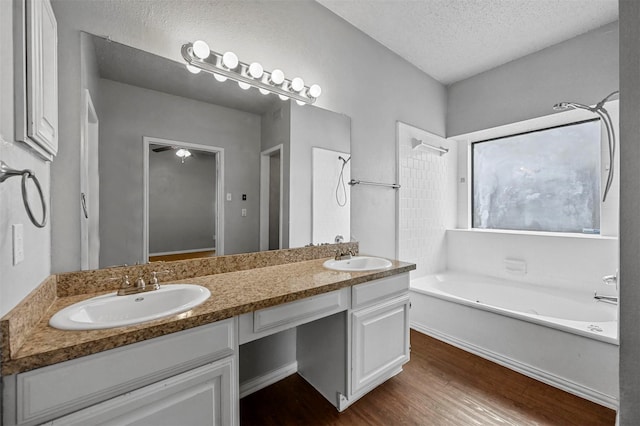 bathroom with a tub to relax in, vanity, wood-type flooring, and a textured ceiling