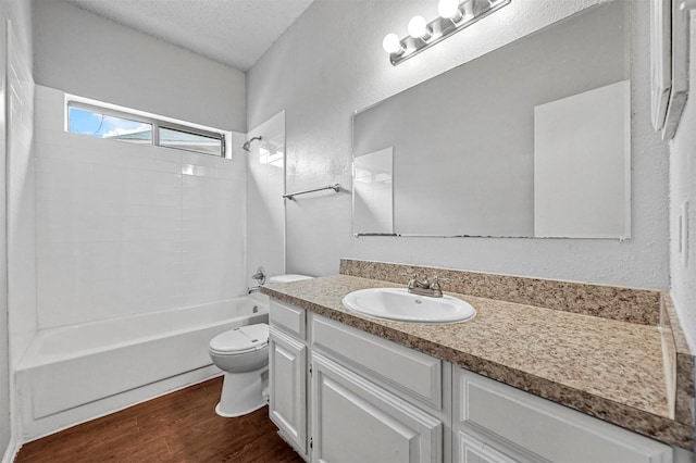 full bathroom featuring toilet, wood-type flooring, a textured ceiling, shower / tub combination, and vanity