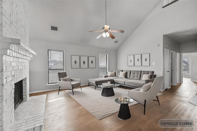 living room featuring hardwood / wood-style flooring, plenty of natural light, high vaulted ceiling, and a brick fireplace