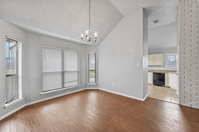 interior space with vaulted ceiling, an inviting chandelier, and light wood-type flooring