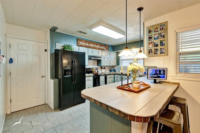 kitchen with a kitchen bar, tasteful backsplash, kitchen peninsula, pendant lighting, and black appliances