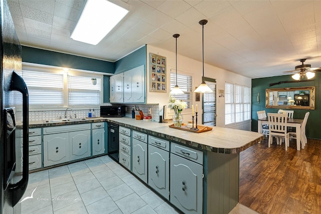 kitchen featuring tasteful backsplash, kitchen peninsula, sink, and black appliances