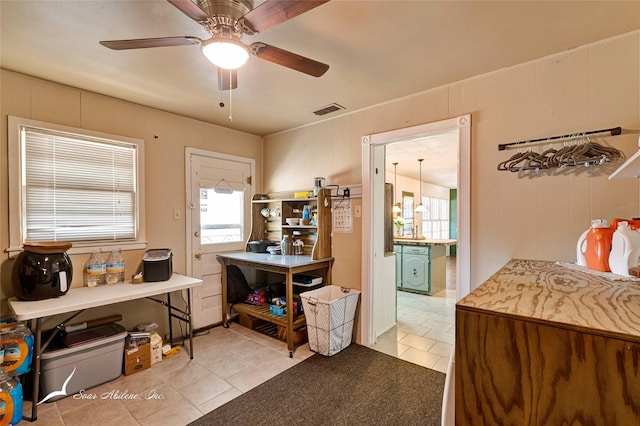 office space featuring ceiling fan, wooden walls, and light tile patterned floors