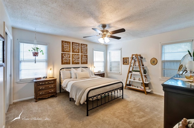 carpeted bedroom featuring ceiling fan, multiple windows, and a textured ceiling