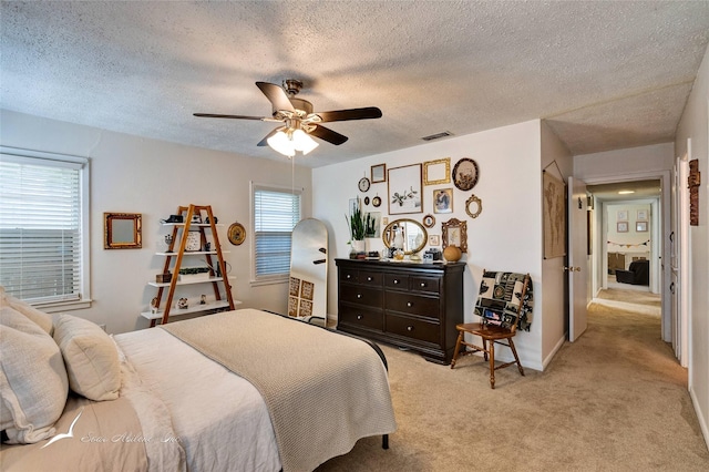 carpeted bedroom featuring multiple windows, a textured ceiling, and ceiling fan