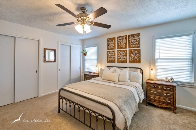 bedroom with two closets, light colored carpet, and ceiling fan