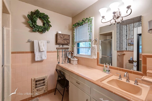 bathroom featuring a shower with door, vanity, heating unit, and tile walls