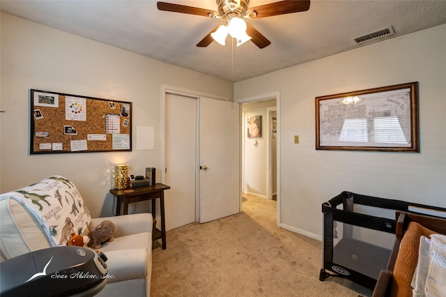 living area featuring light carpet, a textured ceiling, and ceiling fan