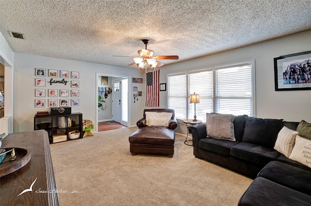 living room with ceiling fan, light carpet, and a textured ceiling