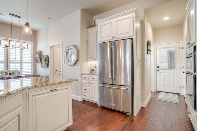 kitchen featuring white cabinetry, high end refrigerator, backsplash, dark hardwood / wood-style flooring, and light stone countertops