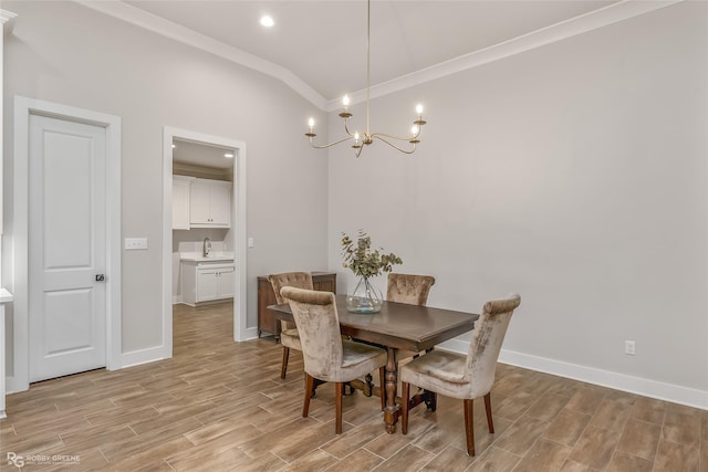 dining space with sink, vaulted ceiling, ornamental molding, and a chandelier