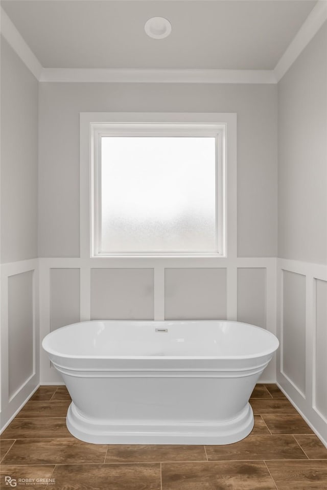 bathroom with a healthy amount of sunlight, a tub to relax in, and ornamental molding