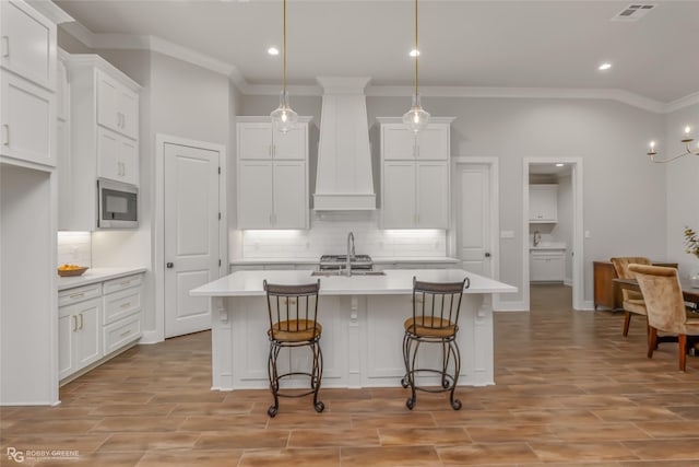 kitchen featuring appliances with stainless steel finishes, custom range hood, and white cabinets