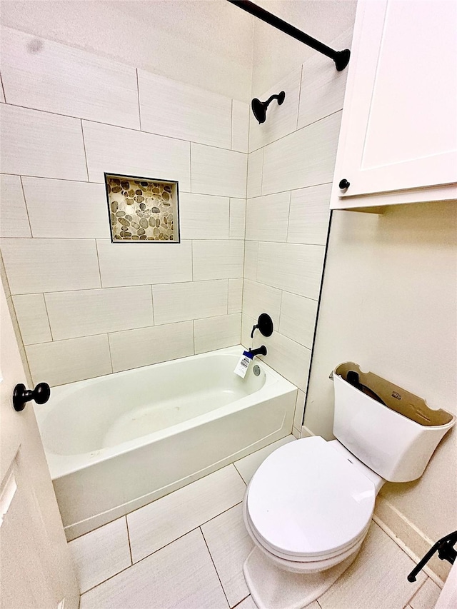 bathroom featuring tiled shower / bath, toilet, and tile patterned flooring