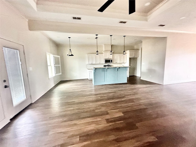 kitchen with pendant lighting, dark hardwood / wood-style floors, an island with sink, and white cabinets