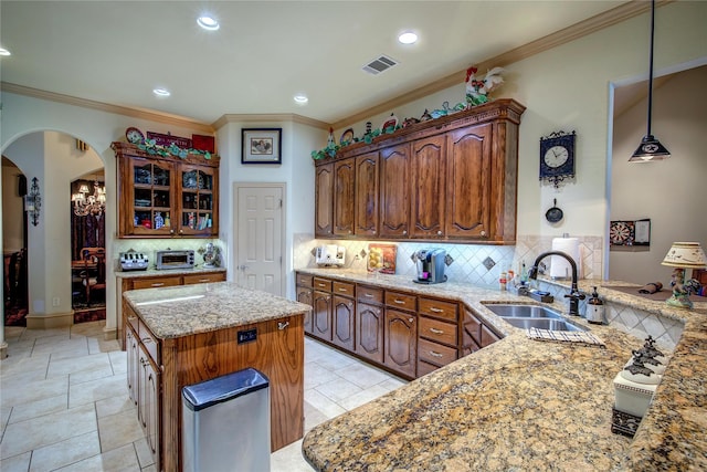 kitchen featuring tasteful backsplash, sink, kitchen peninsula, and a center island