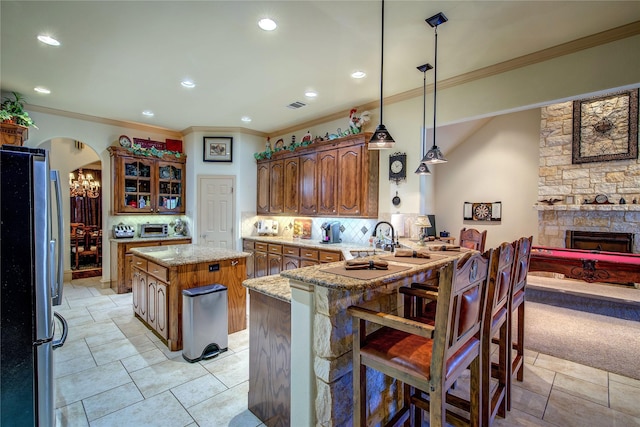 kitchen featuring stainless steel fridge, backsplash, hanging light fixtures, a center island, and kitchen peninsula