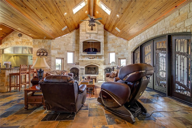 living room with a stone fireplace, high vaulted ceiling, a skylight, beamed ceiling, and wood ceiling