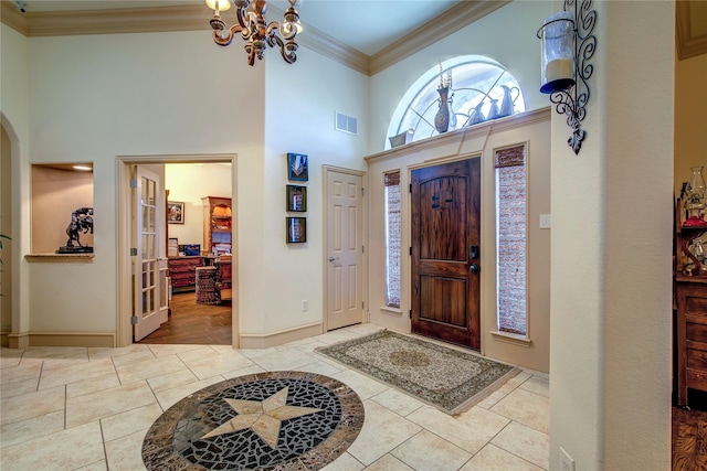 entrance foyer featuring ornamental molding, a towering ceiling, and a chandelier