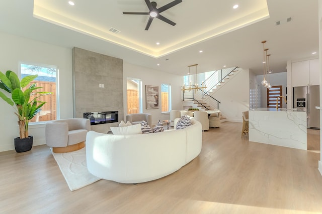 living room featuring light hardwood / wood-style flooring, a fireplace, and a raised ceiling