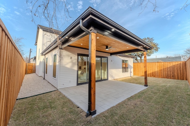 rear view of property featuring ceiling fan, a patio area, and a lawn