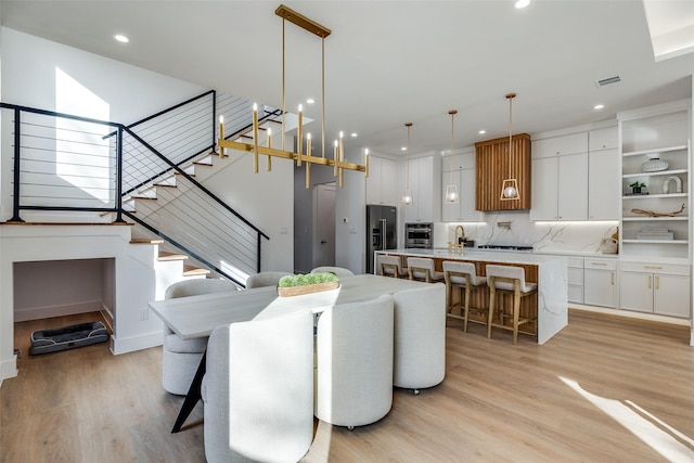 living room featuring sink, a notable chandelier, and light wood-type flooring