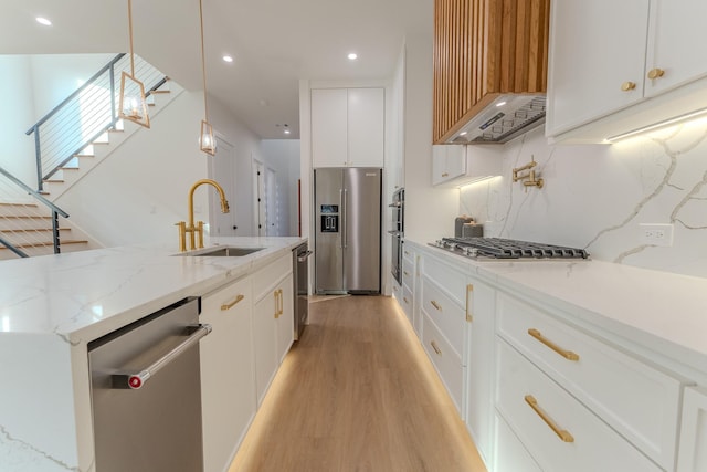 kitchen with pendant lighting, sink, stainless steel appliances, light stone counters, and white cabinets