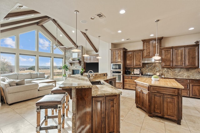 kitchen featuring a large island, pendant lighting, beam ceiling, and decorative backsplash