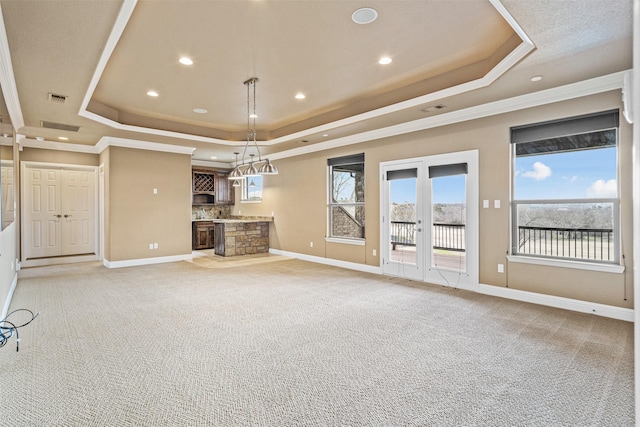 unfurnished living room with french doors, light colored carpet, and a raised ceiling