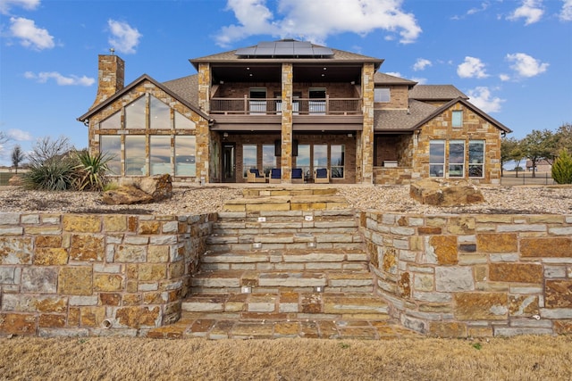 rear view of property featuring a balcony and solar panels