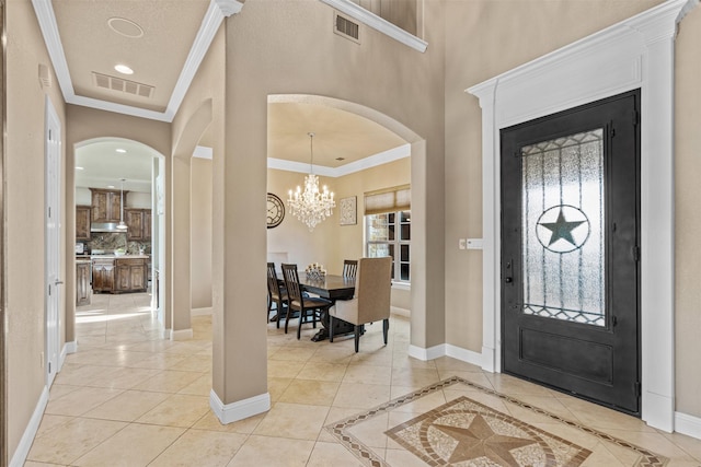 tiled entrance foyer with an inviting chandelier and ornamental molding