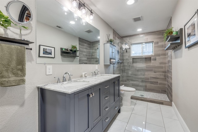 bathroom with vanity, toilet, tile patterned flooring, and a tile shower