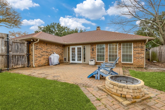 back of property with french doors, a patio, a yard, and a fire pit