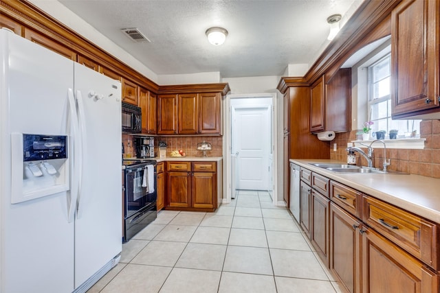 kitchen with light tile patterned flooring, tasteful backsplash, sink, black appliances, and a textured ceiling