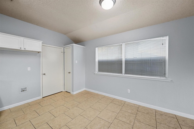 unfurnished bedroom featuring lofted ceiling, light tile patterned floors, a textured ceiling, and a closet