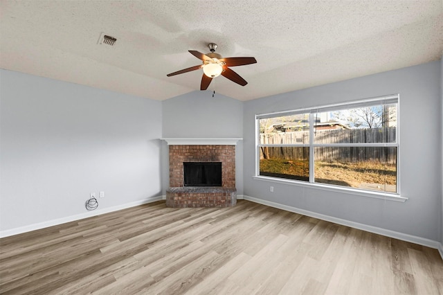 unfurnished living room featuring ceiling fan, a fireplace, a textured ceiling, and light hardwood / wood-style flooring