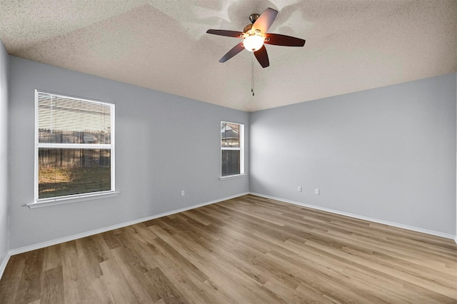 spare room with ceiling fan, plenty of natural light, a textured ceiling, and light hardwood / wood-style floors