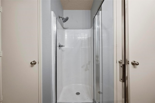 bathroom with a textured ceiling and a shower with shower door