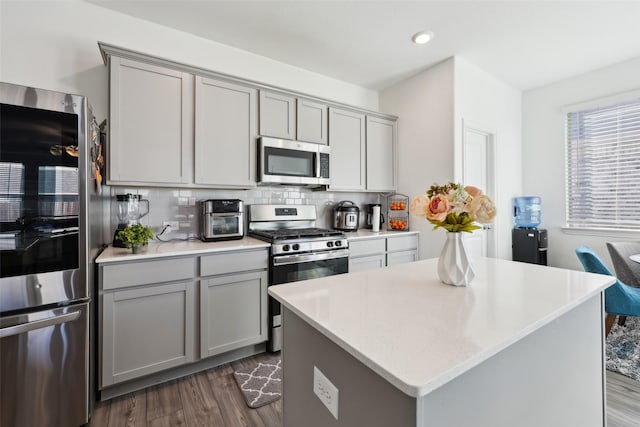 kitchen with stainless steel appliances, a center island, gray cabinetry, and decorative backsplash