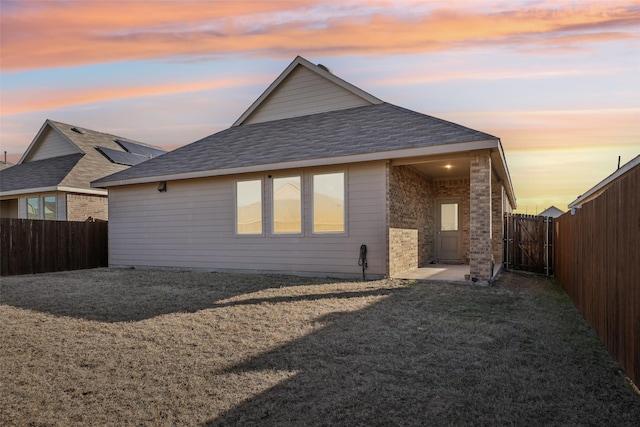 back house at dusk with a lawn